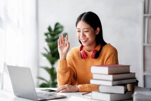 female student using laptop in an online meeting with hand raised